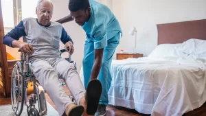 a man in a wheelchair with a nurse helping him in Nursing Homes