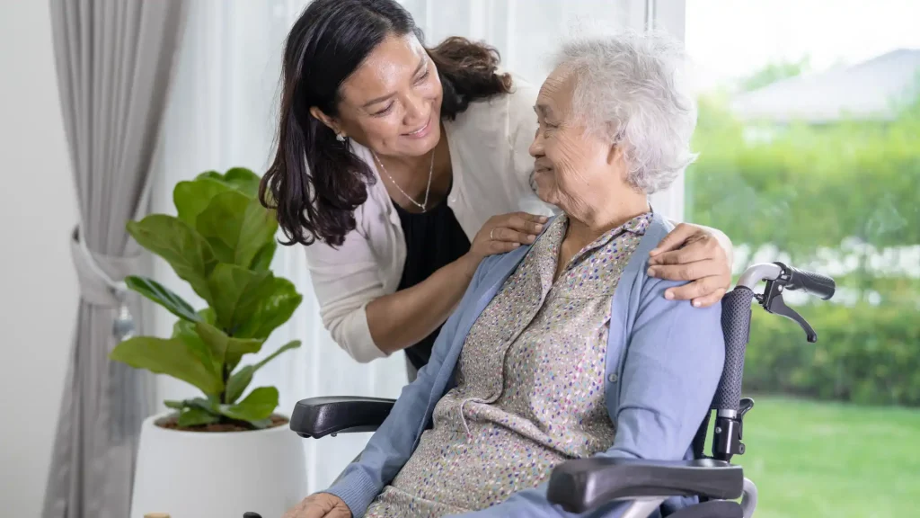 Caregiver gently comforting elderly woman in a wheelchair