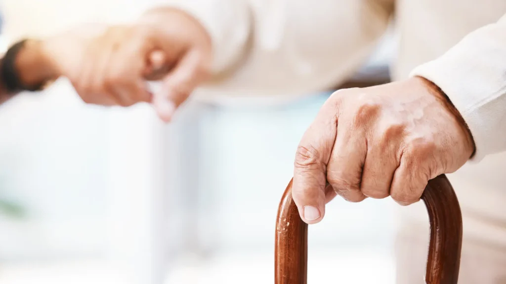 Close-up of a person’s hand gripping a cane.